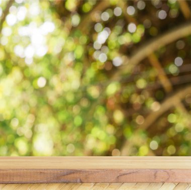 Doğanın arka planında güneş ışığı parlıyor ve odağını kaybediyor. Kare arkaplanda ürün gösterimi için tahta tablo.