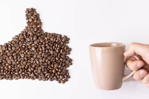 Granos de café dibujados a mano en el lado derecho, una mano masculina sostiene la taza ligera — Foto de Stock