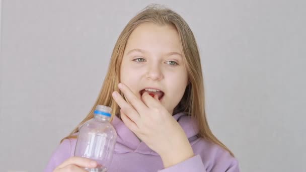 Meisje van Europese verschijning drinkt vitaminen en drinkt water een fles — Stockvideo