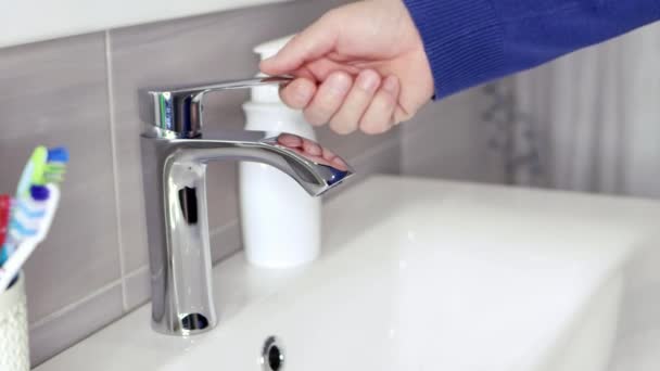 Un homme allume le robinet dans la salle de bain, mais pas d'eau coule. — Video