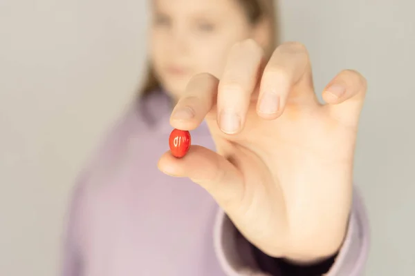 Menina segurando vitamina vermelha em suas mãos close-up em um fundo borrado — Fotografia de Stock