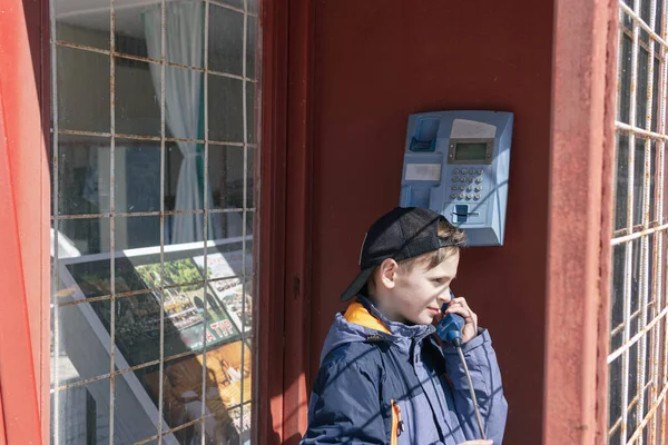 Menino de aparência europeia na cabine telefônica está falando ao telefone — Fotografia de Stock