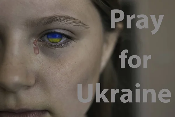Trauriges Kindergesicht mit den Augen der ukrainischen Flagge und einer Träne — Stockfoto