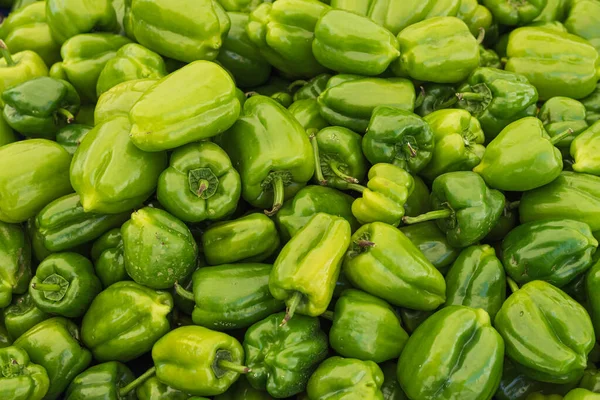 A lot of green peppers in the market on the counter, the background — Stock Photo, Image