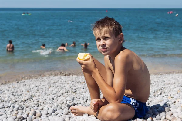 Tanned Blond Boy Blond Hair Sitting Beach Eating Apple Sea — ストック写真