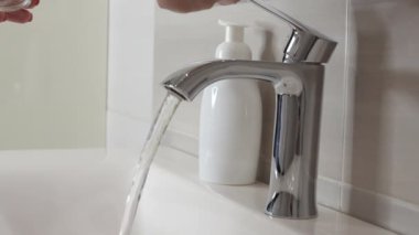 female hands open the faucet and draw water into a transparent glass close-up, bathroom. High quality FullHD footage