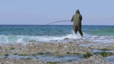 a man fishes in the sea or river in a rubber suit with a fishing rod in his hands. High quality FullHD footage