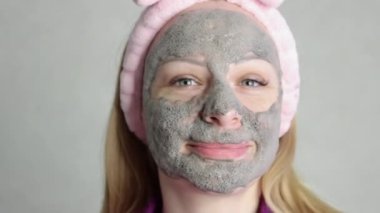 girl with blond hair and European appearance ,close-up on the face .Smiling gray bubble face mask on her face.the concept of home care milking the girls, slow motion. High quality FullHD footage