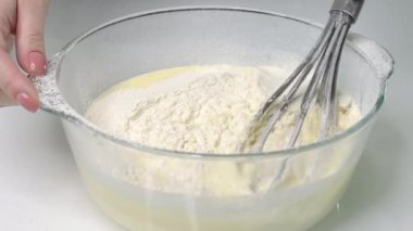 close-up glass bowl with batter slow motion gray whisk stirring the dough close-up isolated on white background. High quality FullHD footage