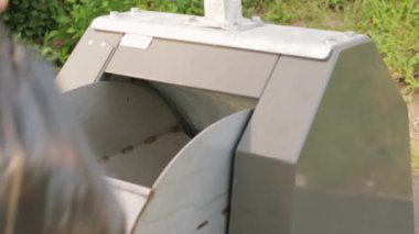 girl throws a black bag with garbage into a container, close-up on her hands. Female hands throw garbage into a special garbage container. The concept of cleanliness and order. High quality 4k footage
