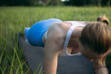 Hafif, atletik görünümlü, mavi taytlı ve beyaz başlıklı bir kız, bir tahtanın üzerinde duruyor. Spor yapmak için gri bir halıya çıkıyor. Sağlıklı yaşam tarzı kavramı. Yüksek kalite fotoğraf