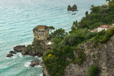 Turkuaz körfez, kumlu sahil, yeşil dağlar ve bitkiler, mavi gökyüzü, beyaz bulutlar arka plan, Capo Vaticano kaya platformu, Calabria, güney İtalya.