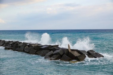 Turkuaz körfez, kumlu sahil, yeşil dağlar ve bitkiler, mavi gökyüzü, beyaz bulutlar arka plan, Capo Vaticano kaya platformu, Calabria, güney İtalya.