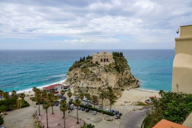 Turkuaz körfez, kumlu sahil, yeşil dağlar ve bitkiler, mavi gökyüzü, beyaz bulutlar arka plan, Capo Vaticano kaya platformu, Calabria, güney İtalya.