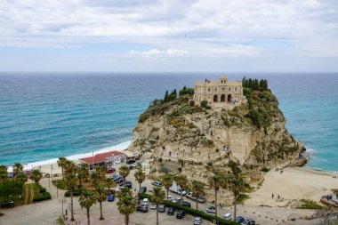 Turkuaz körfez, kumlu sahil, yeşil dağlar ve bitkiler, mavi gökyüzü, beyaz bulutlar arka plan, Capo Vaticano kaya platformu, Calabria, güney İtalya.