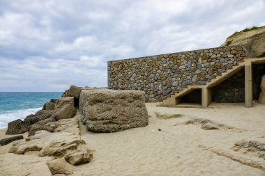 Turkuaz körfez, kumlu sahil, yeşil dağlar ve bitkiler, mavi gökyüzü, beyaz bulutlar arka plan, Capo Vaticano kaya platformu, Calabria, güney İtalya.