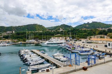 Turkuaz körfez, kumlu sahil, yeşil dağlar ve bitkiler, mavi gökyüzü, beyaz bulutlar arka plan, Capo Vaticano kaya platformu, Calabria, güney İtalya.