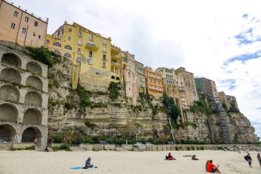 Turkuaz körfez, kumlu sahil, yeşil dağlar ve bitkiler, mavi gökyüzü, beyaz bulutlar arka plan, Capo Vaticano kaya platformu, Calabria, güney İtalya.