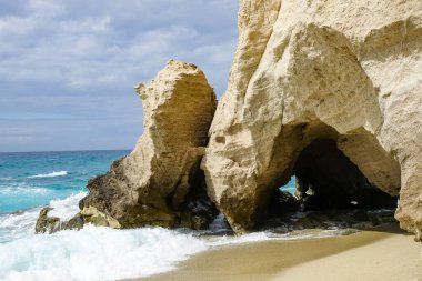 Turkuaz körfez, kumlu sahil, yeşil dağlar ve bitkiler, mavi gökyüzü, beyaz bulutlar arka plan, Capo Vaticano kaya platformu, Calabria, güney İtalya.