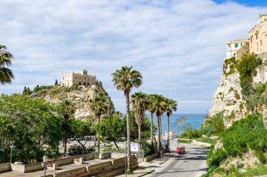 Turkuaz körfez, kumlu sahil, yeşil dağlar ve bitkiler, mavi gökyüzü, beyaz bulutlar arka plan, Capo Vaticano kaya platformu, Calabria, güney İtalya.