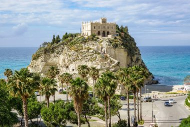 Turkuaz körfez, kumlu sahil, yeşil dağlar ve bitkiler, mavi gökyüzü, beyaz bulutlar arka plan, Capo Vaticano kaya platformu, Calabria, güney İtalya.