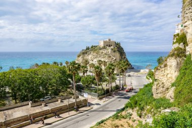 Turkuaz körfez, kumlu sahil, yeşil dağlar ve bitkiler, mavi gökyüzü, beyaz bulutlar arka plan, Capo Vaticano kaya platformu, Calabria, güney İtalya.