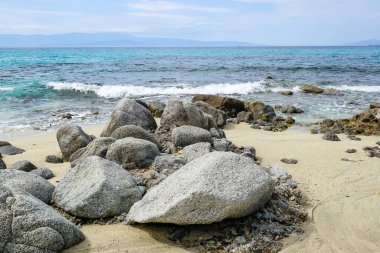 Turkuaz körfez, kumlu sahil, yeşil dağlar ve bitkiler, mavi gökyüzü, beyaz bulutlar arka plan, Capo Vaticano kaya platformu, Calabria, güney İtalya.
