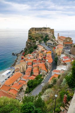 Turkuaz körfez, kumlu sahil, yeşil dağlar ve bitkiler, mavi gökyüzü, beyaz bulutlar arka plan, Capo Vaticano kaya platformu, Calabria, güney İtalya.