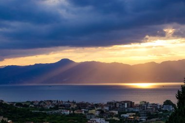 Turkuaz körfez, kumlu sahil, yeşil dağlar ve bitkiler, mavi gökyüzü, beyaz bulutlar arka plan, Capo Vaticano kaya platformu, Calabria, güney İtalya.