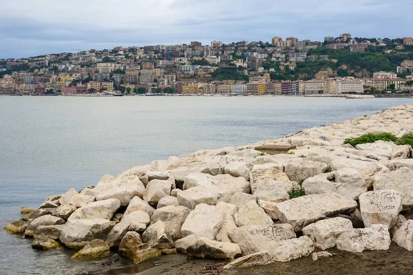 Turkuaz körfez, kumlu sahil, yeşil dağlar ve bitkiler, mavi gökyüzü, beyaz bulutlar arka plan, Capo Vaticano kaya platformu, Calabria, güney İtalya.