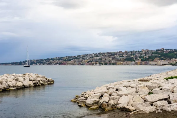 Turkuaz körfez, kumlu sahil, yeşil dağlar ve bitkiler, mavi gökyüzü, beyaz bulutlar arka plan, Capo Vaticano kaya platformu, Calabria, güney İtalya.