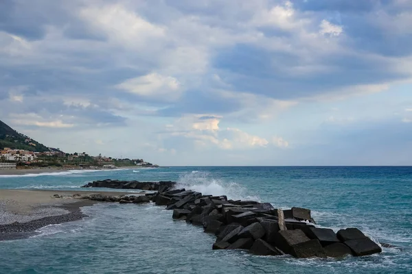 Turkuaz körfez, kumlu sahil, yeşil dağlar ve bitkiler, mavi gökyüzü, beyaz bulutlar arka plan, Capo Vaticano kaya platformu, Calabria, güney İtalya.