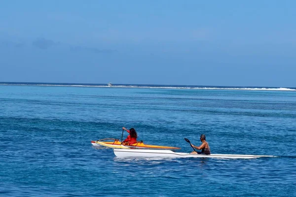 坐在蓝色皮划艇上的男人 在海边坐着一艘白色冲浪船 — 图库照片