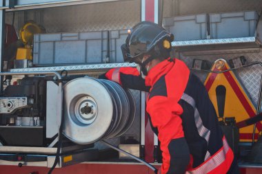 İtfaiyeci yangını söndürmek için itfaiye aracından aletler alıyor.