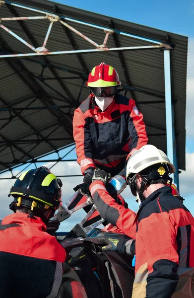 Üniforma ve kask giyen bir grup itfaiyeci bir araba kazasında kurtarma operasyonu düzenledi.