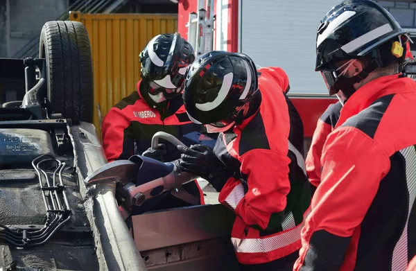 Üniforma ve kask giyen bir grup itfaiyeci bir araba kazasında kurtarma operasyonu düzenledi.