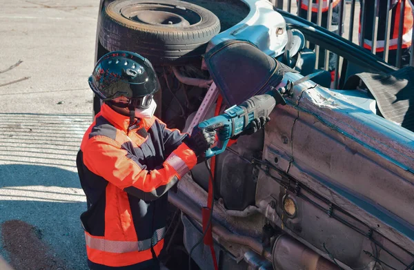 İtfaiyeci bir trafik kazasının kurbanını kurtarmak için araba açmaya çalışıyor.