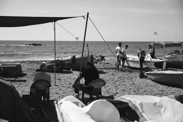 İspanya 'nın Malaga plajındaki bir grup gence bakan iki yaşlı emekli balıkçı.