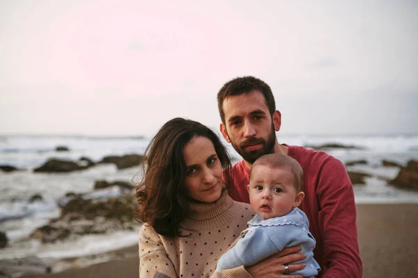 Geleneksel genç aile mutlu poz veriyor. Günü plajda geçiriyorlar.
