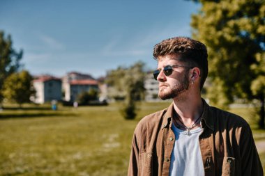 Güneş gözlüklü modaya uygun bir çocuk ve yeşil çayır üzerinde telif alanı olan ciddi bir ifade.