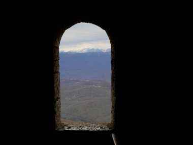 Eski binadaki taş pencereden karlı dağlara bak