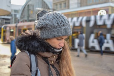 Kafasında şapkayla şehirde yürüyen yalnız bir kadının portresi.
