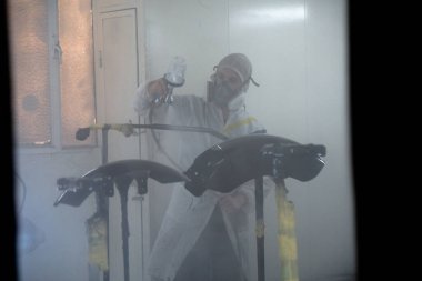 Duman içinde bir sprey boya kabininde boyacı.