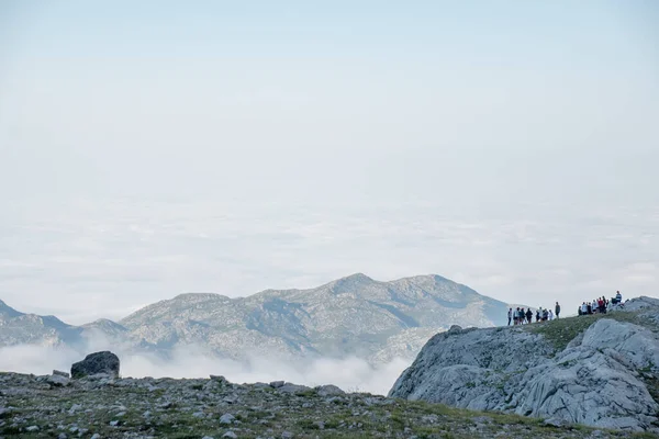 groups of people on the top of a mountain watching the clouds