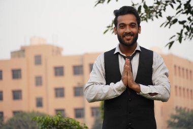 Güzel Hintli adam kameraya bakarken namaste hareketi yapıyor.