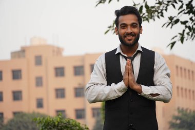 Güzel Hintli adam kameraya bakarken namaste hareketi yapıyor.