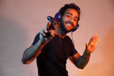 Delikanlı evde Joystick 'le maç kazanıyor ve kulaklık takmak rahatlatıyor.