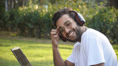 Bilgisayarlı genç bir öğrenci video görüşmesi sırasında kulaklık takıyor. Laptop resimli bir adam.