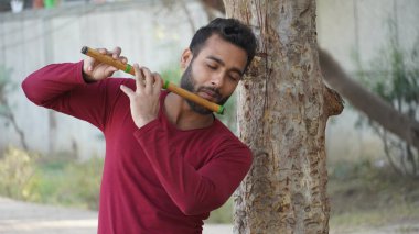 Genç bir adam flüt çalıyor.