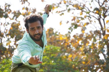 Kriket oynarken kriket topunu atan adam.